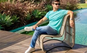 homem sentado em poltrona ao lado da piscina