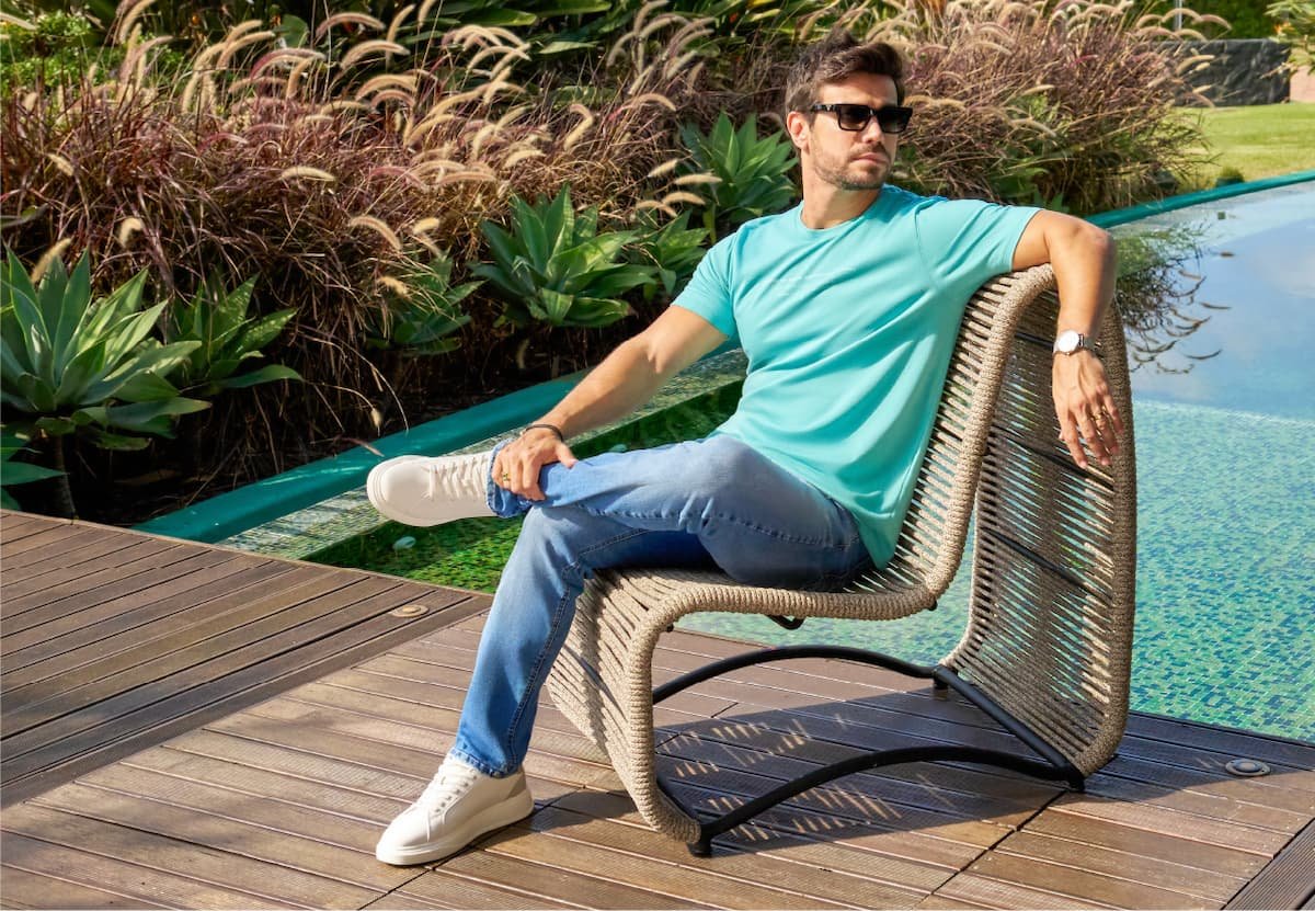 homem sentado em poltrona ao lado da piscina