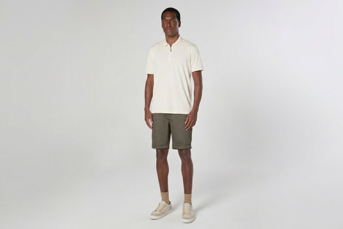 modelo usando camisa polo e bermuda shino em fundo cinza
