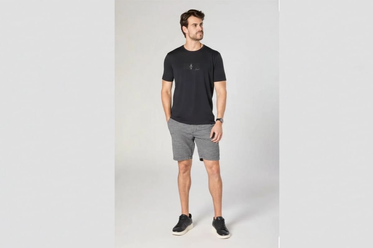 modelo usando camiseta preta e bermuda shino em fundo cinza